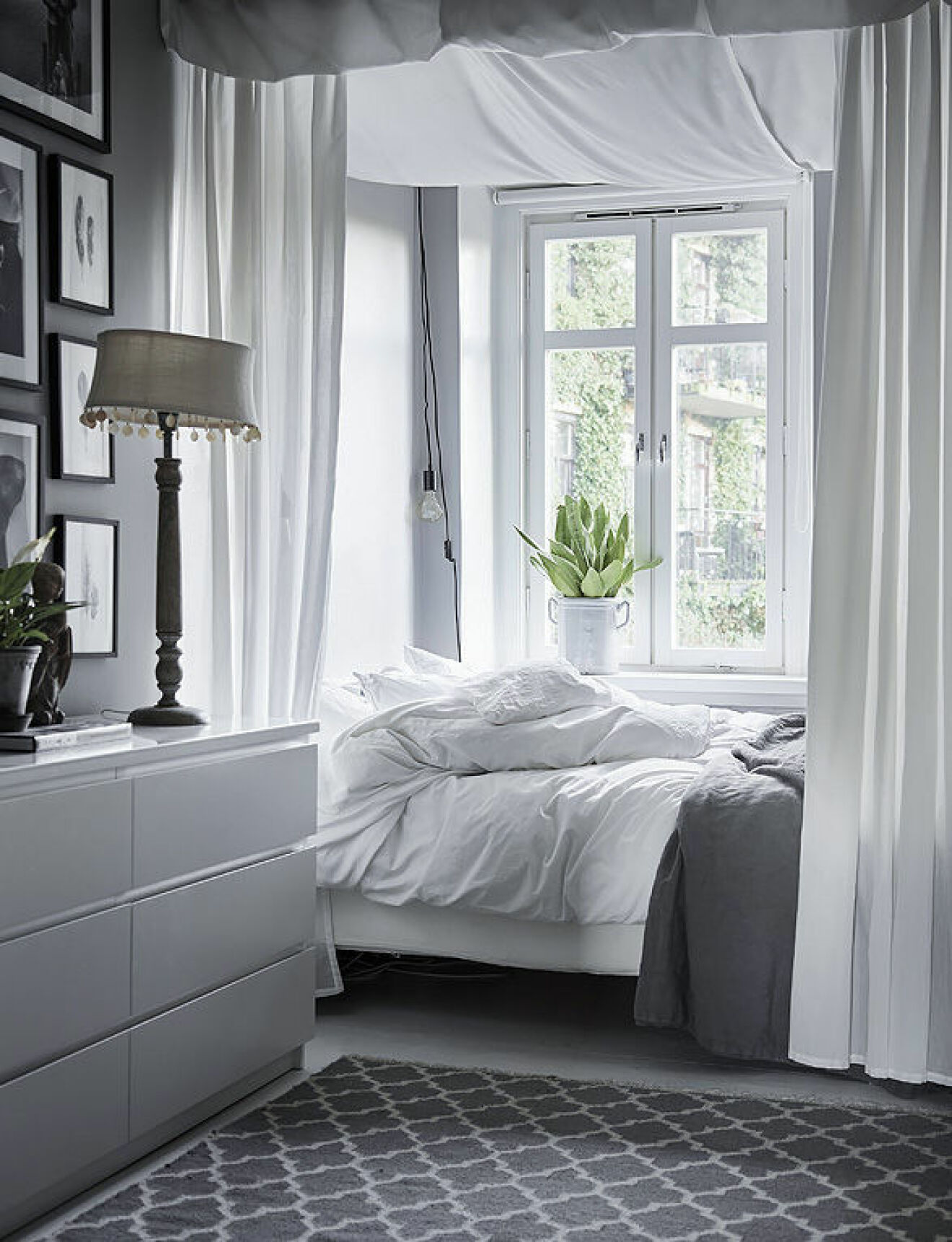 Cosy bedroom with grey and white colours. Fabric over the bed. Scandinavian interior decoration ideas and inspiration. 