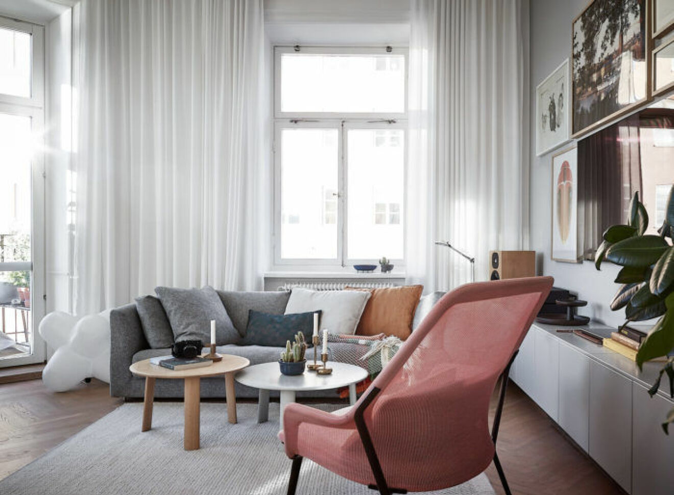 Scandinavian decoration and ideas. Livingroom with grey decor and a pink chair. Long, white curtains.