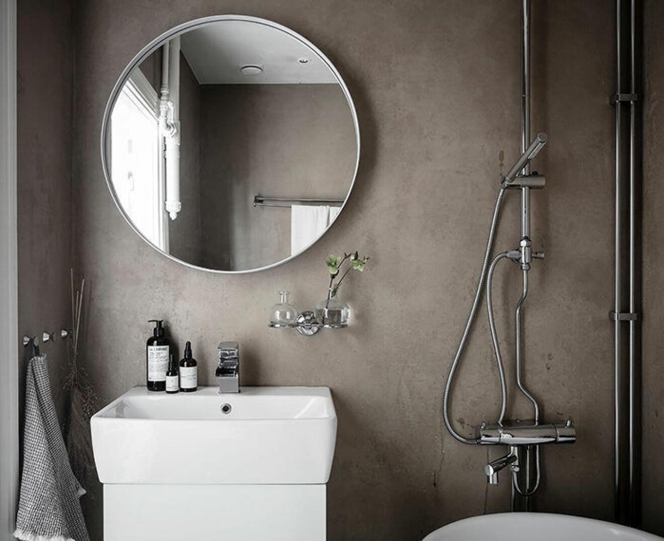 Stor rund spegel i snyggt litet badrum