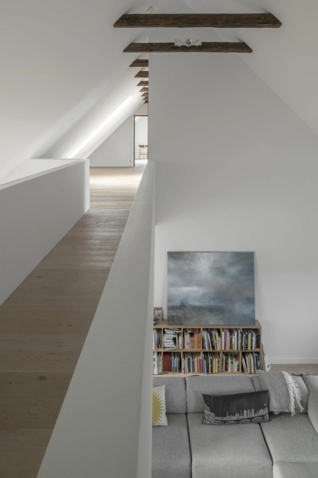 Stramt under takstolarna. Bro mellan sovrum och allrum. Oljemålning av Österlenskonstnären Kit Alexi. Design- och arkitekturböcker.