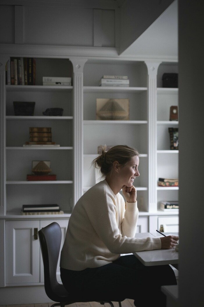 Antonia vid skrivbordet på ovanvåningen. Den platsbyggda bokhyllan bakom henne designades av den tidigare ägaren som var arkitekt. Inbyggd bokhylla bakom Antonia.