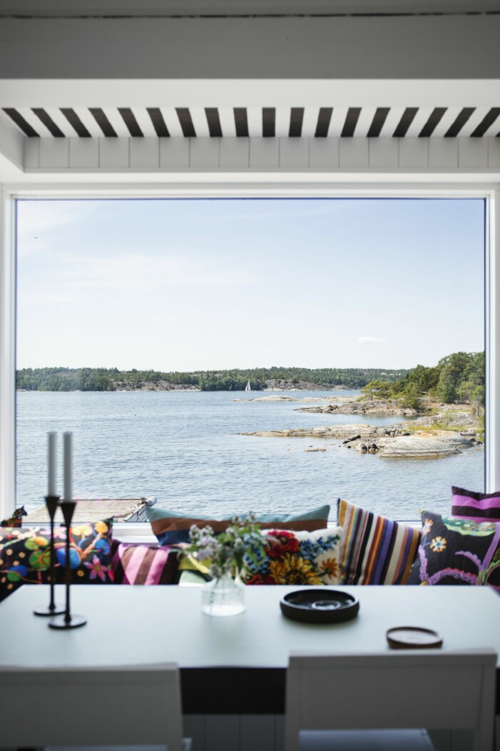 Inramad utsikt. Bäddad med kuddar klädda i tyger från bland annat Svenskt tenn och Marocko. Inramad utsikt över vattnet.