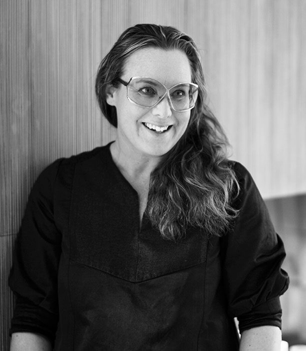 <em>Jenny Askenfors vid väggen som också är den öppna spisen mellan kök och vardagsrum. »Jag gillar att mönstret är vågigt här och att det går vidare till gardinerna som man kan dra för längs hela vardagsrummet.«</em> jenny askenfors