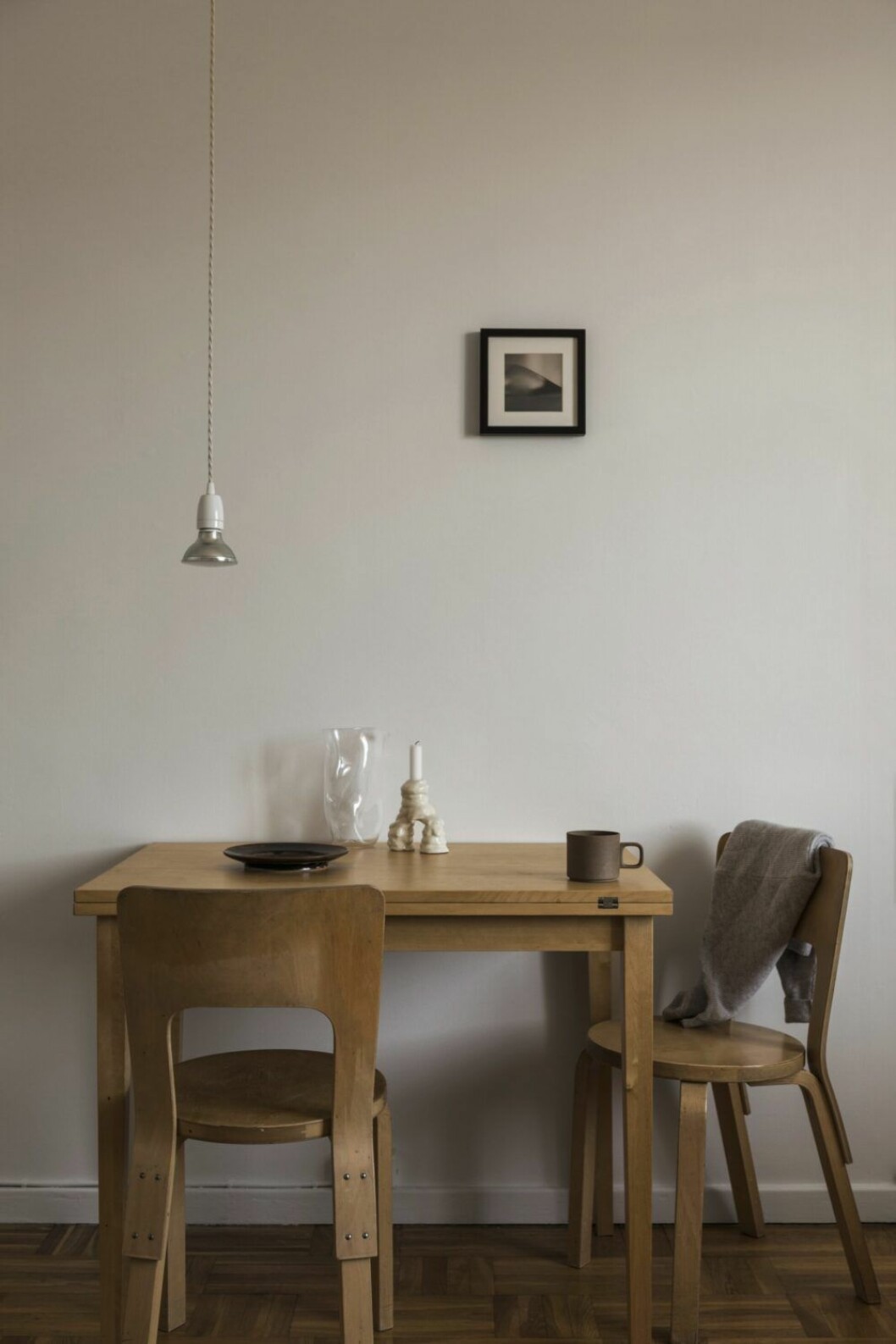 Stolar Modell 66 av Alvar Aalto, Artek. Lampan har Jessica satt ihop av delar från Creative cables. Inramat urklipp från ett magasin. Bordet plockade hon upp när någon ville bli av med möbler i ett trapphus. Karaff, Ebba von Wachenfeldt. Keramikfat, Calle Forsberg. Kopp Hasami från Type O.