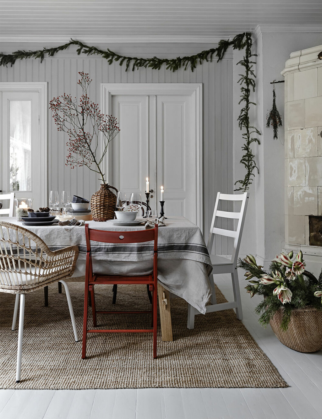 Gör upp en plan för julstädningen för att sedan kunna pynta och göra hemmet mysigt! Foto: Ikea Julinredning med röd stol, girlang av granris och kvist med röda bär hos Ikea