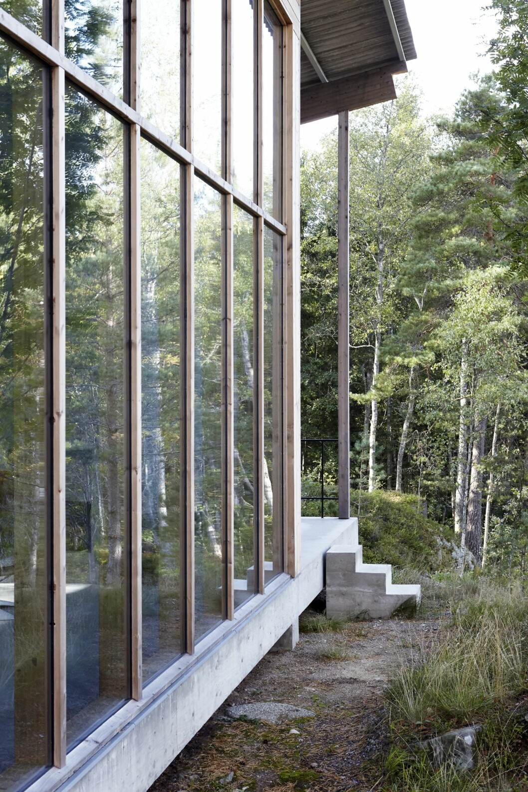 Den lilla trappan leder från terrassen ner mot sjön. Kika in i arkitektritade huset. Här lever man spartanskt utan el och vatten.