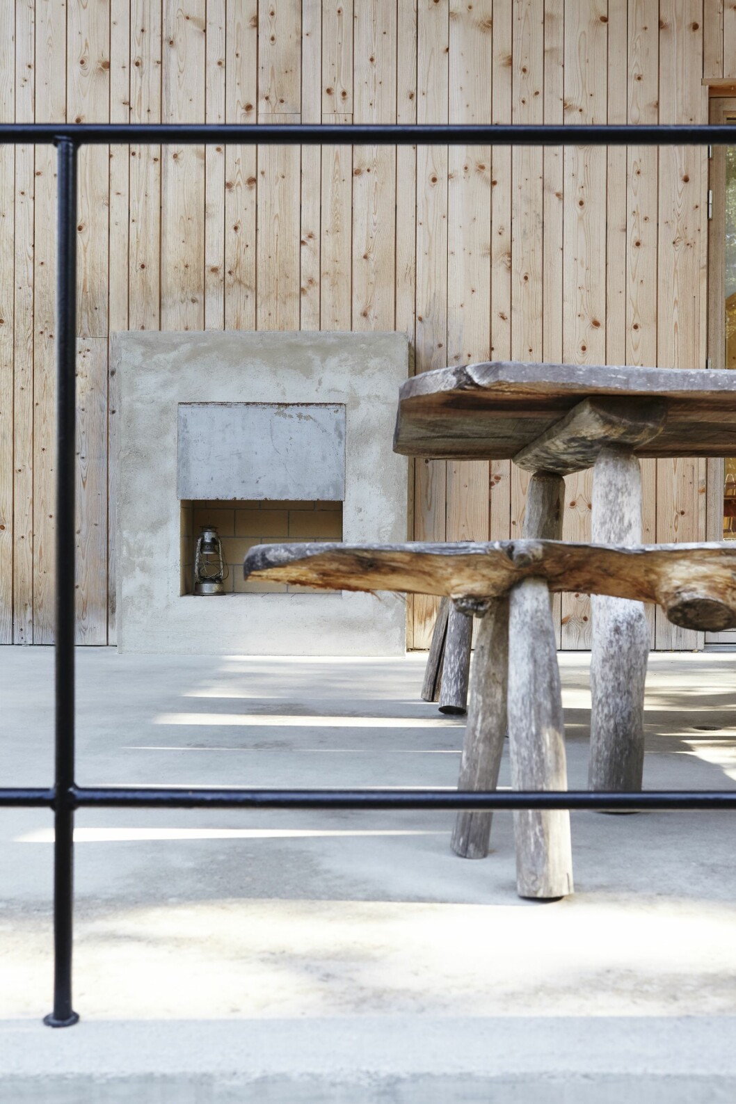 Vardagsrummets öppna spis är tillgänglig även från terrassen. Möblerna har beställarna själva snickrat. Kika in i arkitektritade huset. Här lever man spartanskt utan el och vatten.