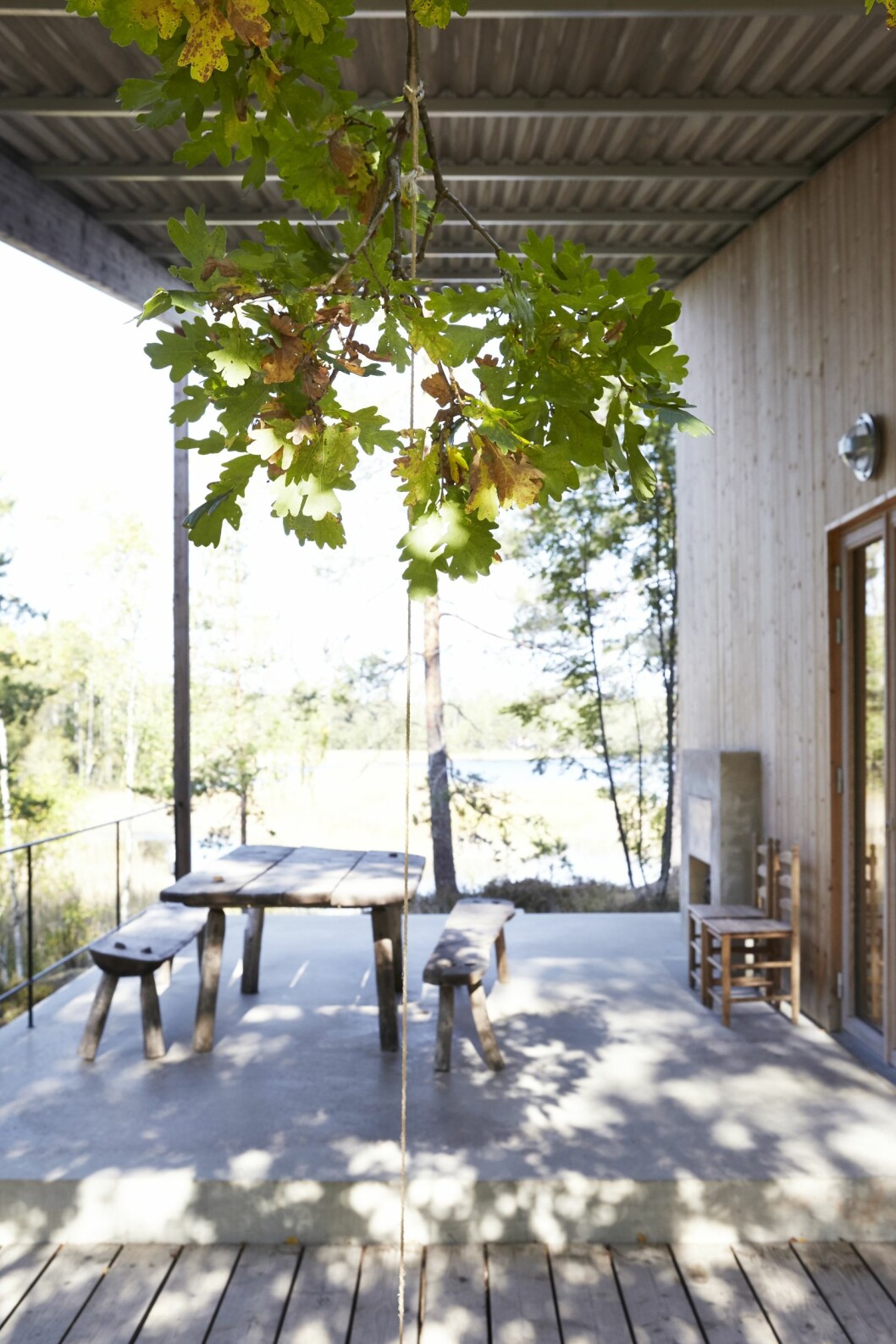 Insidans betonggolv fortsätter ut genom fasaden och bildar terrass. Den skuggande ekens grenar formas med hjälp av rep. Kika in i arkitektritade huset. Här lever man spartanskt utan el och vatten.