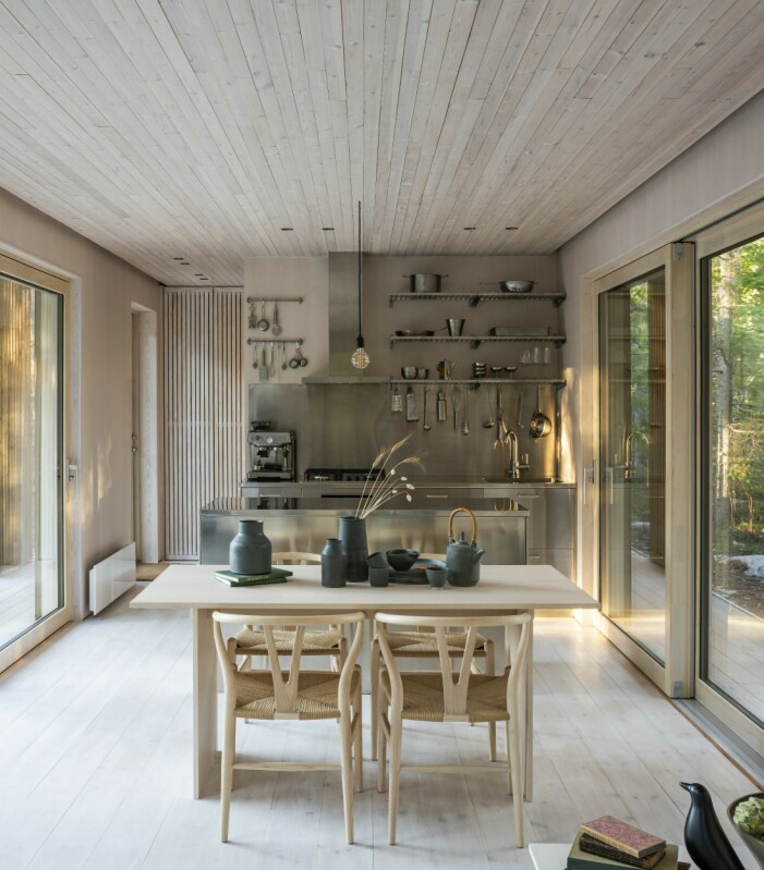På båda sidor om köket kan glaspartierna öppnas så att man i princip står ute under tak och lagar mat. Keramiken på bordet, Vasakeramik av Therese Hagström Olsson. Stolar Hans Wegner, Carl Hansen. Köksön av Decor Steel, köket har f ö ritats av Emelie Holmberg. Kök i ljust trä.