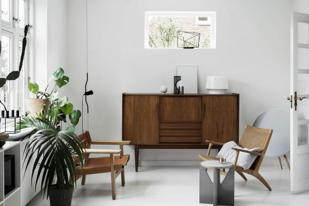 Egen design blandas med inropade favoritmöbler och danska klassiker. Teakskänk köpt på loppis. Vit bordslampa, Muuto. Framför den runda B&O-högtalaren står Hans Wegners CH25 Lounge chair. Grå pall, Kristina Dam Studio. Till vänster den spanska stolen som Kristina avgudar.