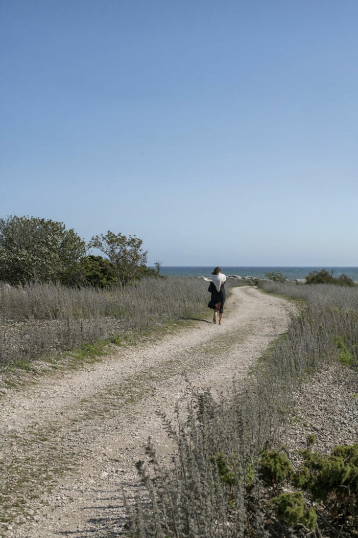 Landskapet, alla spännande utflyktsmål och den sociala sidan av Gotland lockade Malin och hennes familj till att köpa ett kalkstenshus i Hamra socken. Kvinna gående längs en väg på Gotland.