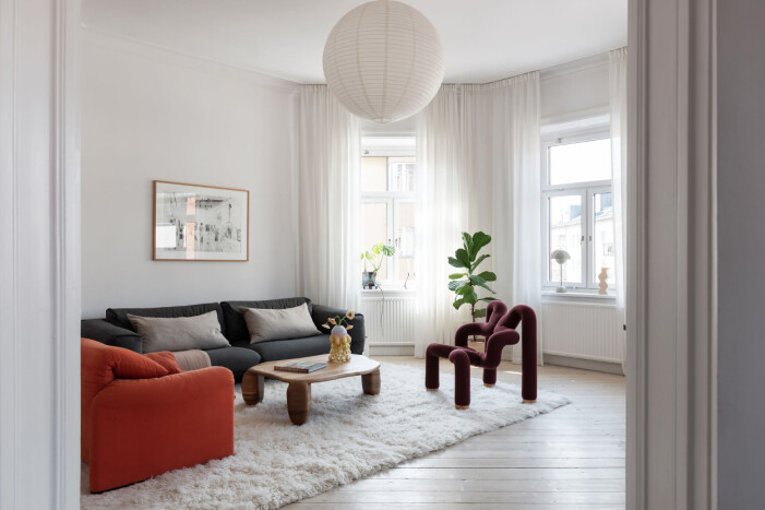 Från det oktagonformade vardagsrummet har man utsikt över tre olika väderstreck och Södermalms takåsar – inte fy skam. Oktagonformat vardagsrum inrett med matta med lång lugg, soffa och fåtölj