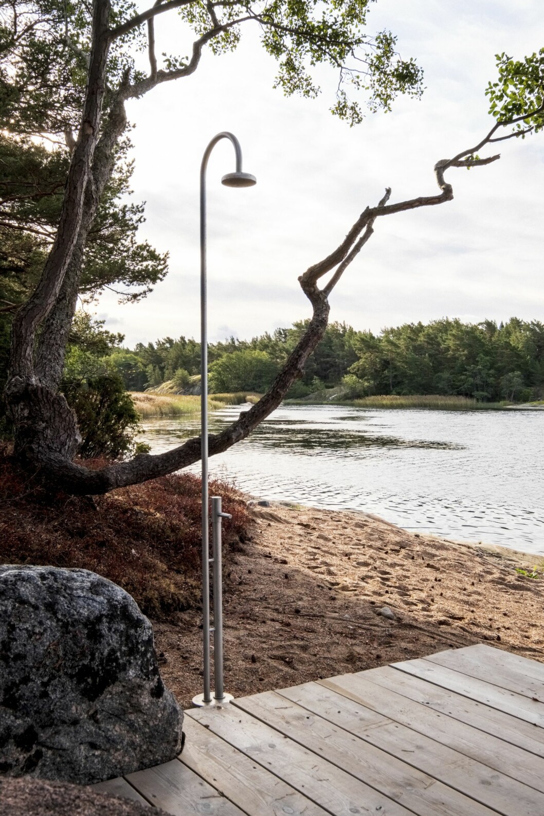 Stranden med egen utomhusdusch. Tänk att få starta morgonen med ett dopp och en dusch här. Utomhusdusch vid stranden i studentritade huset Villa Furuholmen.