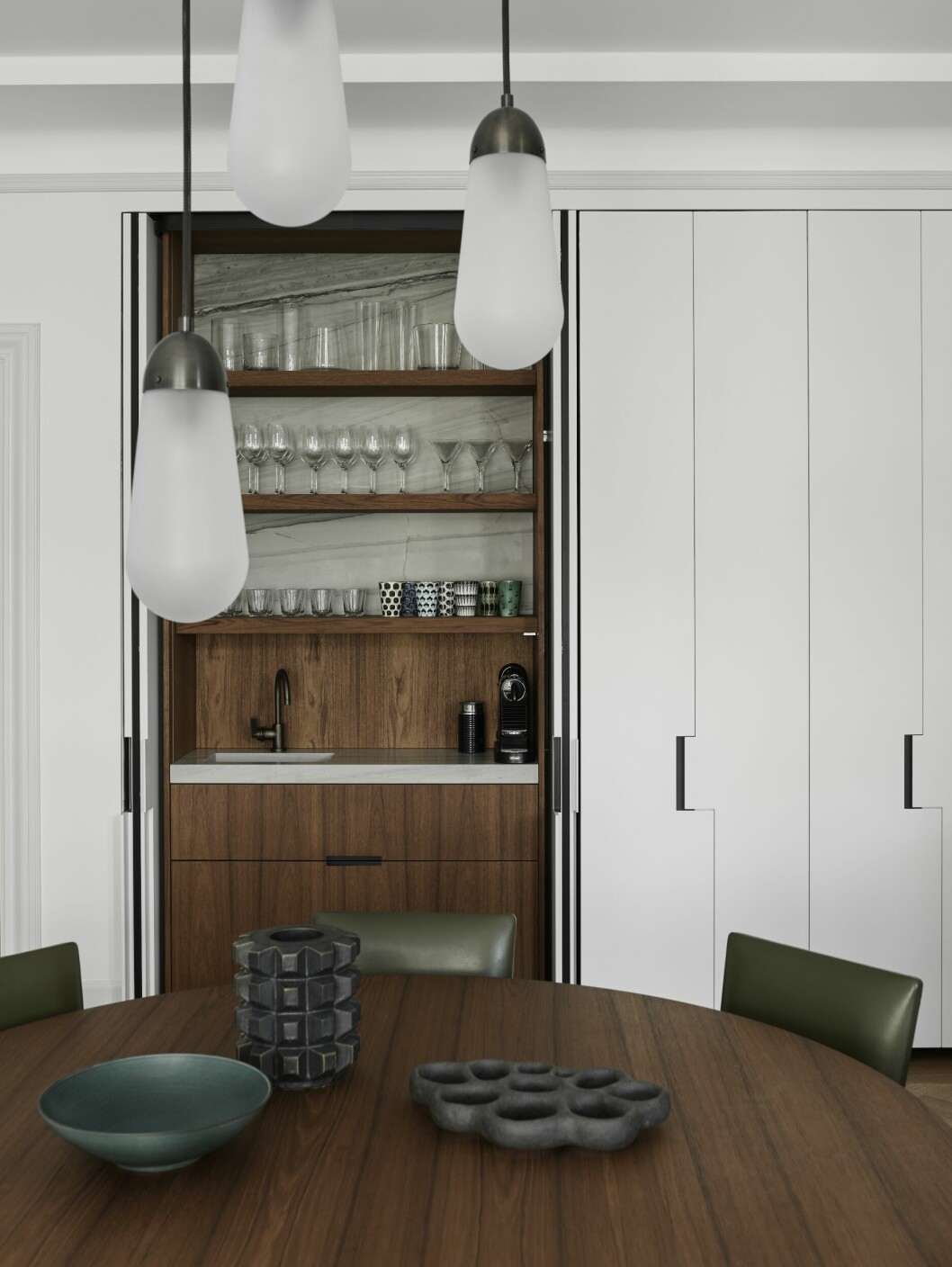 I köket finns en lång rad med förvaring, en del utgörs av ett pocketskåp med vask och kaffebryggare i. Joanna gillar pussel och har inspirerats av olika pussellika arkitektoniska element när hon designade skåpsdörrarna. Även köksbordet är designat av Studio Lawahl.