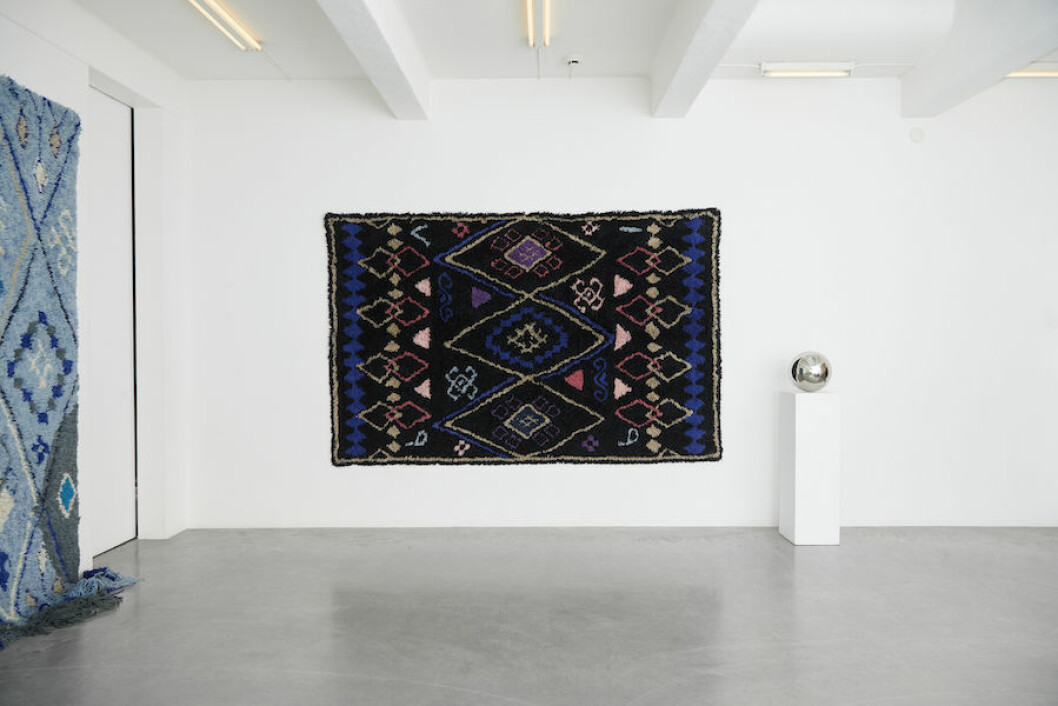 Bild på svart matta upphängd på väggen från Layereds nya mattkollektion Modern Oriental.