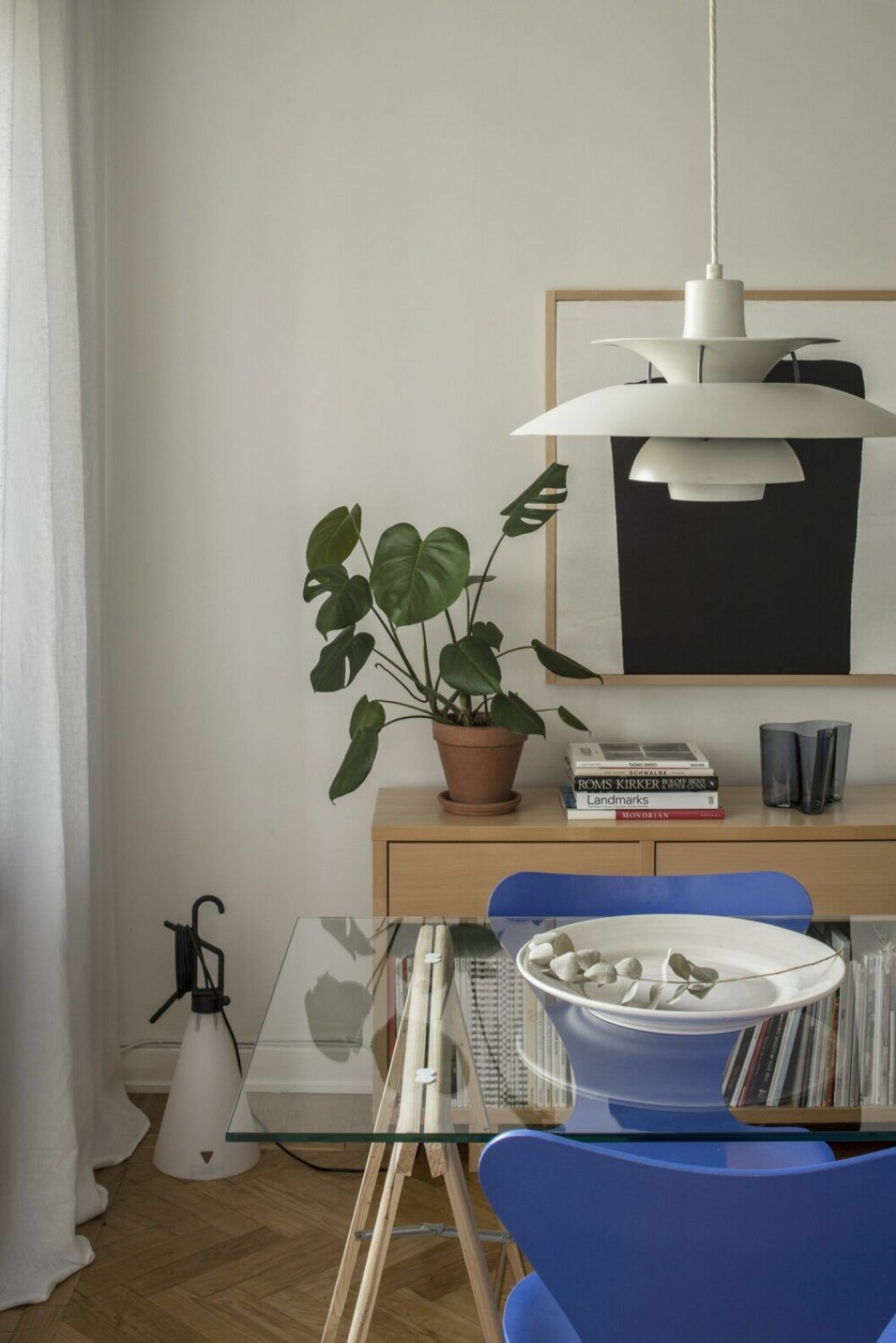 Golvlampa Mayday, design Konstantin Grcic för Flos. Matbord tillverkat av en glasskiva på arbetsbockar från Bauhaus. Lampa PH 5 av Poul Henningsen för Louis Poulsen. Skänk designad av Sebastians mor Tuula Falk. Fat från Mateus. Målning av Sebastian. Vas, Alvar Aalto, Iittala. Matplats