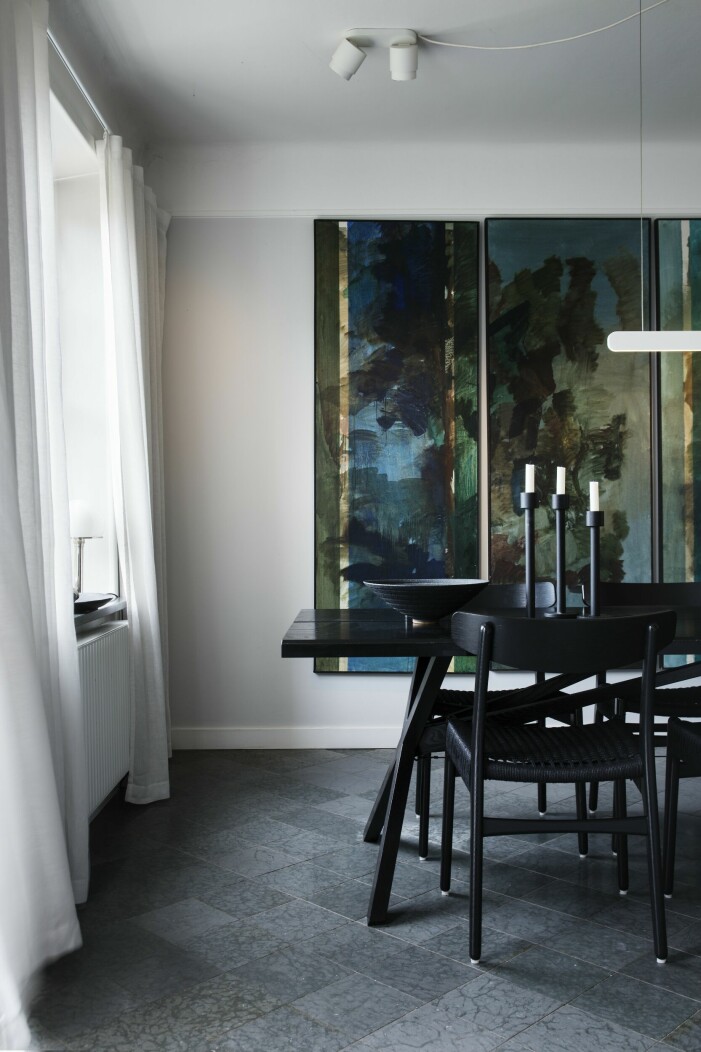 Matsalens präglas av en oljemålad skog, okänd konstnär. Bordet med en modern »bonnighet« är ritat av Olle Rex. Stolar Hans Wegners CH23, Carl Hansen & søn. Skål av keramikern Sotis Filippides i London. Golv av öländsk kalksten. Matsal med konst.