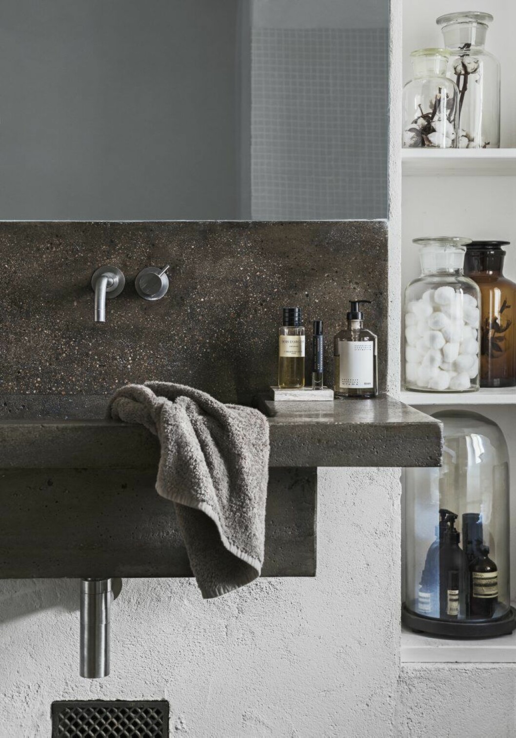 I badrummet har de tidigare ägarna formgjutit ett handfat. Produkter från Frama och Aesop. Glasburkar, Granit.
