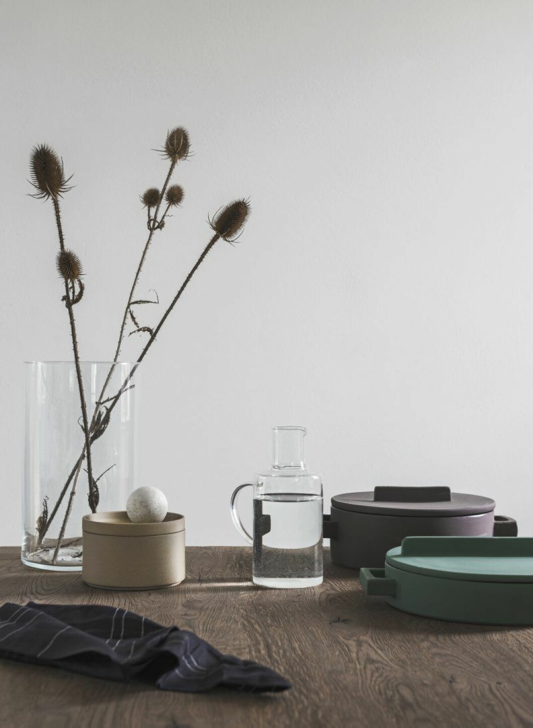 På bordet en cylindervas med torkade kardvädd- stjälkar som Magnus plockat i närheten. Karaff från Granit, serveringskärl från Terracotto och Hasami porcelain, sfär i förstelnat trä.