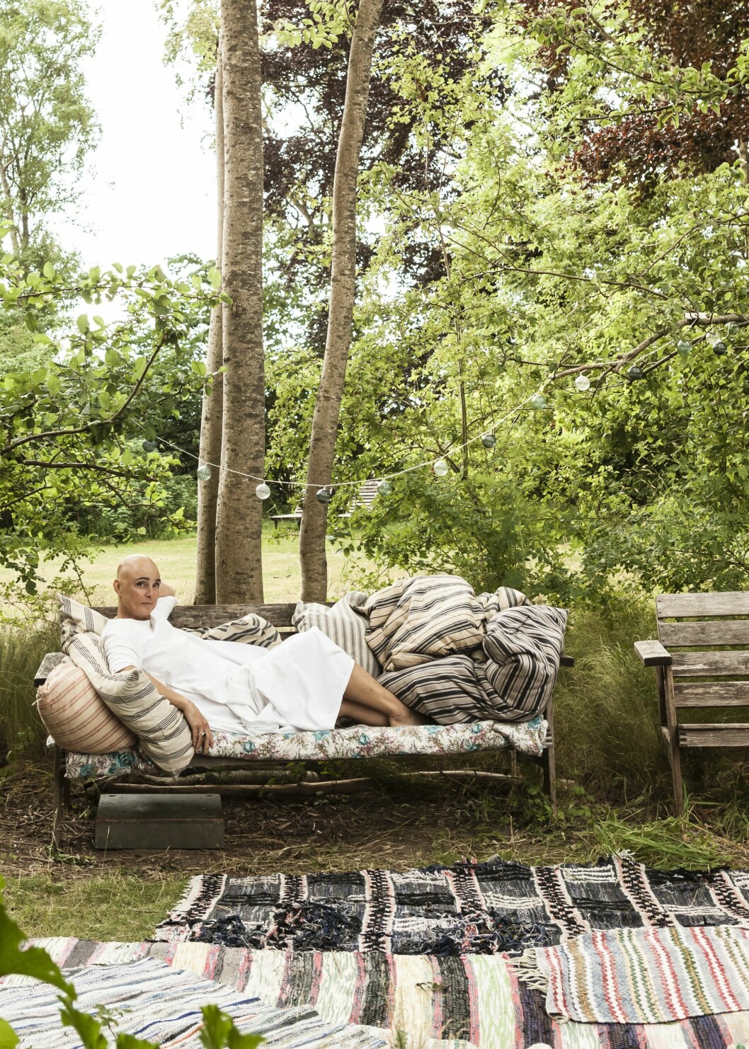 Gamla trasmattor får skapa ett »rum« på en av uteplatserna, bredvid uteköket. Christina i uterummet.