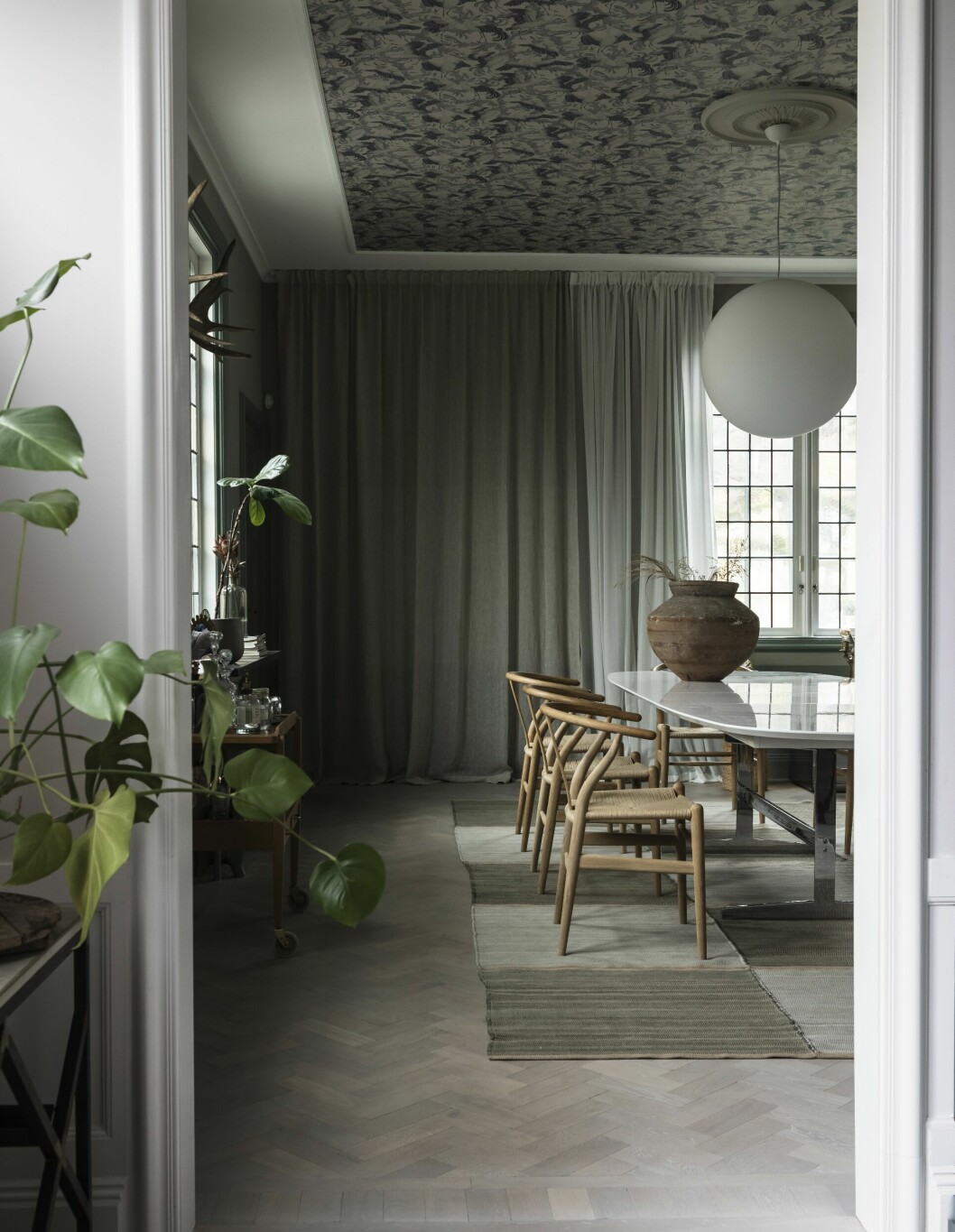 Matrummet har ett ovanligt snyggt innertak: en tapet av Emma von Brömssen. Mer sådant!<br>Parketten är såpad med vitt pigment. Gardiner från Gotain. Matta från Swedish rags. Vintagekruka på bordet från The Straw.