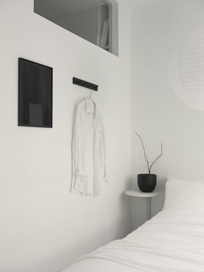 På sovrumsväggen mot köket hänger motivet Raka av Ida Vikfors. Sängbord tillverkat av pallen Frosta från Ikea. Svart kruka i keramik, vintage. Monokromt hemma hos Simon Strömstedt