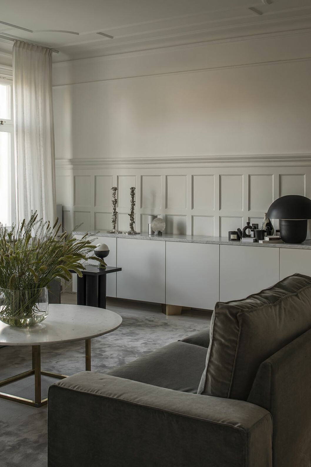 Det är inte bara väggpanelerna som har äldre charm, även taket och fönstren bjuder på romantisk prakt. Najda har matchat arkitekturen med moderna möbler i neutrala färger och geo¬¬metriska former. Nadja vardagsrum2