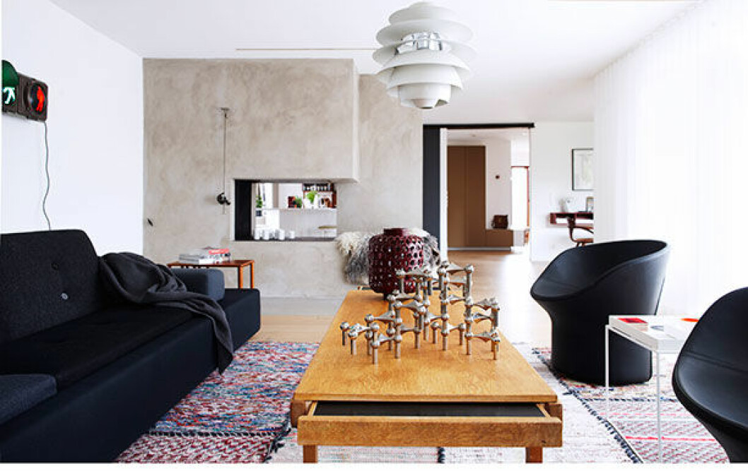 <em>Det ljusa vardagsrummet med kök och hall som fond. Mattan kommer från Jenny Askenfors företag Rugcycle via Bofink/NK Inredning. Soffa, Vitra. Soffbordet i teak från 60-talet är arvegods. Svarta snurrfåtöljer från Swedese är köpta från Lauritz. Det lilla vita bordet från Hay. Herr Gårman-trafikljuset från 70-talet blev vägglampa, köpt i antikaffär i Palma. Taklampan är en P H.</em> nagel ljusstake