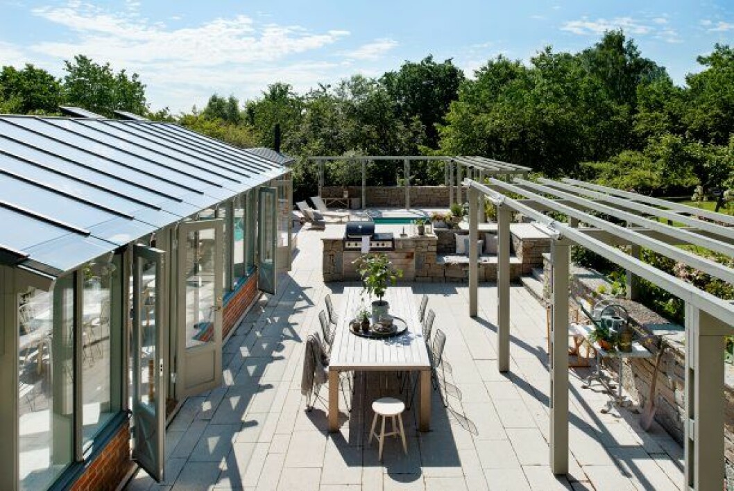 Vy från huset över terrasserna. Här är det lätt att umgås. ”Barnen är här jämt” säger Mikael ”Och wifin fungerar även utomhus vilket de ser som ett extraplus” Stolar, Tio, Massproductions. Pläd, NK Inredning. Pall, Norrgavel. Porslin Matteus/NK Classic Home. Servetter, Linum/NK Classic Home. Kruka, Granit. Flaska med kork, Granit. Växter från Blomsterlandet. Orangeri, Jordens Arkitekter