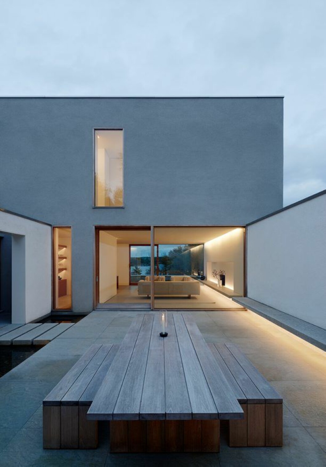 Från gårdsrummet har du fri sikt rakt igenom vardagsrummet och vidare ut över sjön Drevviken. Möblerna är tillverkade i teak och ritade av Pawson själv. Villa Palmgren, John Pawson Limited