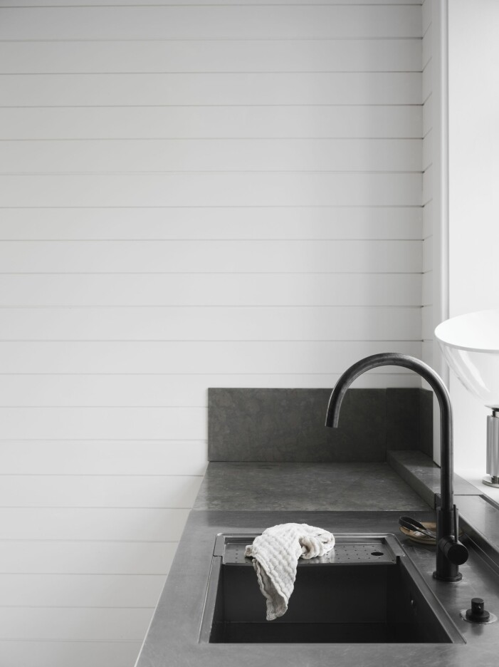 I köket kombineras en kalkstensskiva med rostfri plåt. Den gråsvarta blandaren i färgen Shadow kommer från Primy. Kök med kalkstensskiva i kombination med rostfritt stål hemma hos Pella Hedeby