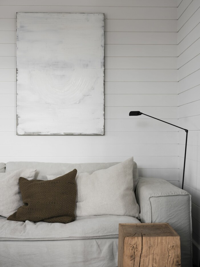 Blick in mot sovrummet som har en mix av textilier ton i ton från Astrid. Mattan Long pile linen från Roots living. Soffan Luca, Melimeli, tavla av Bo Andersson inropad på Bukowskis, lampa Daphine från Lumina och pall Gala, Noorstad. Soffa Luca, från Melimeli i vardagsrummet hemma hos Pella Hedeby