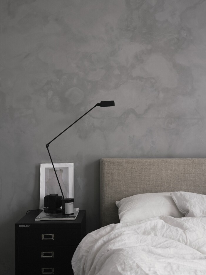 Sovrum med texturer i lager. Vägg putsad med KC14 i nyansen Limestone från Detale Cph. Sänggavel och kappa klädda i textil från Astrid, bäddlinne från Norrgavel, hurts, Bisley, lampa Daphine, Lumina och doftljus, Frama Cph. Sovrum med texturfärg på väggen hemma hos stylisten Pella Hedeby