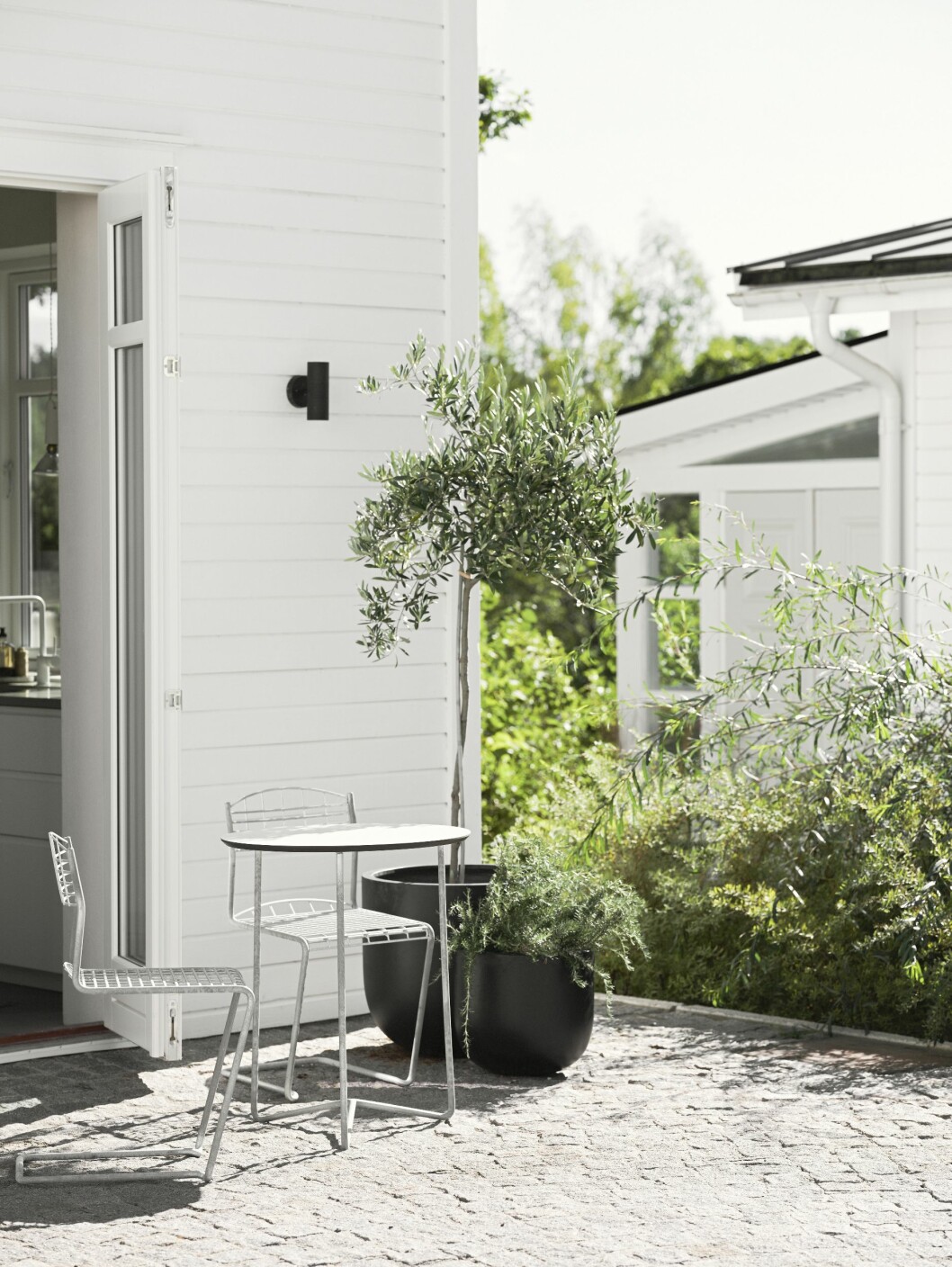 Kafégrupp i solen, stolar och bord i modellen High Tech från Grythyttan, stora krukor från Bauhaus. Kafégrupp från Grythyttan och stora krukor från Bauhaus.