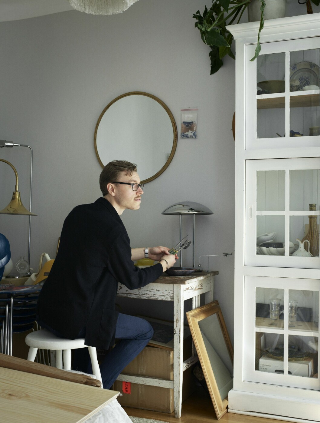 Sigge Billgren vid sitt skrivbord omringad av loppisfynd som ger honom inspiration. Turkosa bestick från franska Melron.