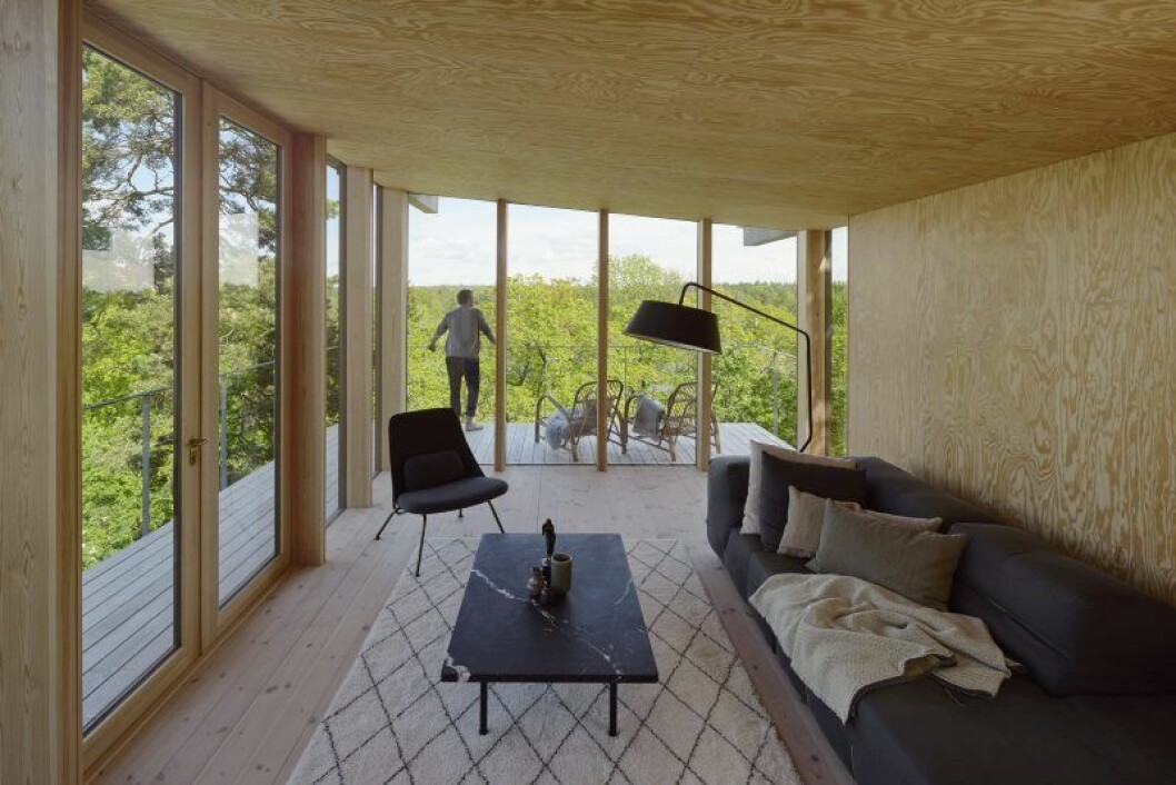 Vardagsrum med utsikt över trädkronorna. Soffa från B&B, fåtölj Strain Prostoria, matta Kasthall. Lampa Ligne roset. Bordet har Andreas ritat själv med skiva av matt Nero Marquina-marmor. Stora vasen på bordet av paret Triller i Tobo. Lilla vasen, Gunnar Wennerberg. Victor Heinrich Seifert har skulpterat bronsstatyetten som påminner Andreas om hans mamma. Sommarhus Andreas Martin-Löf
