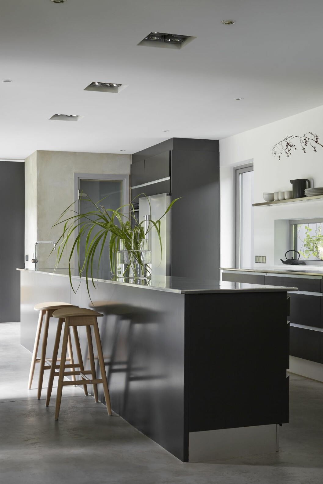 Kök från JKE design med rejäla bänkskivor och inga överskåp. Längst bort sonen Sixtens sovrum. Svalen går att gå in i. Barstolar från Massproductions. Från köket leder en dörr ut i växthuset. Golv av microcement. Köket i arkitektritade huset.