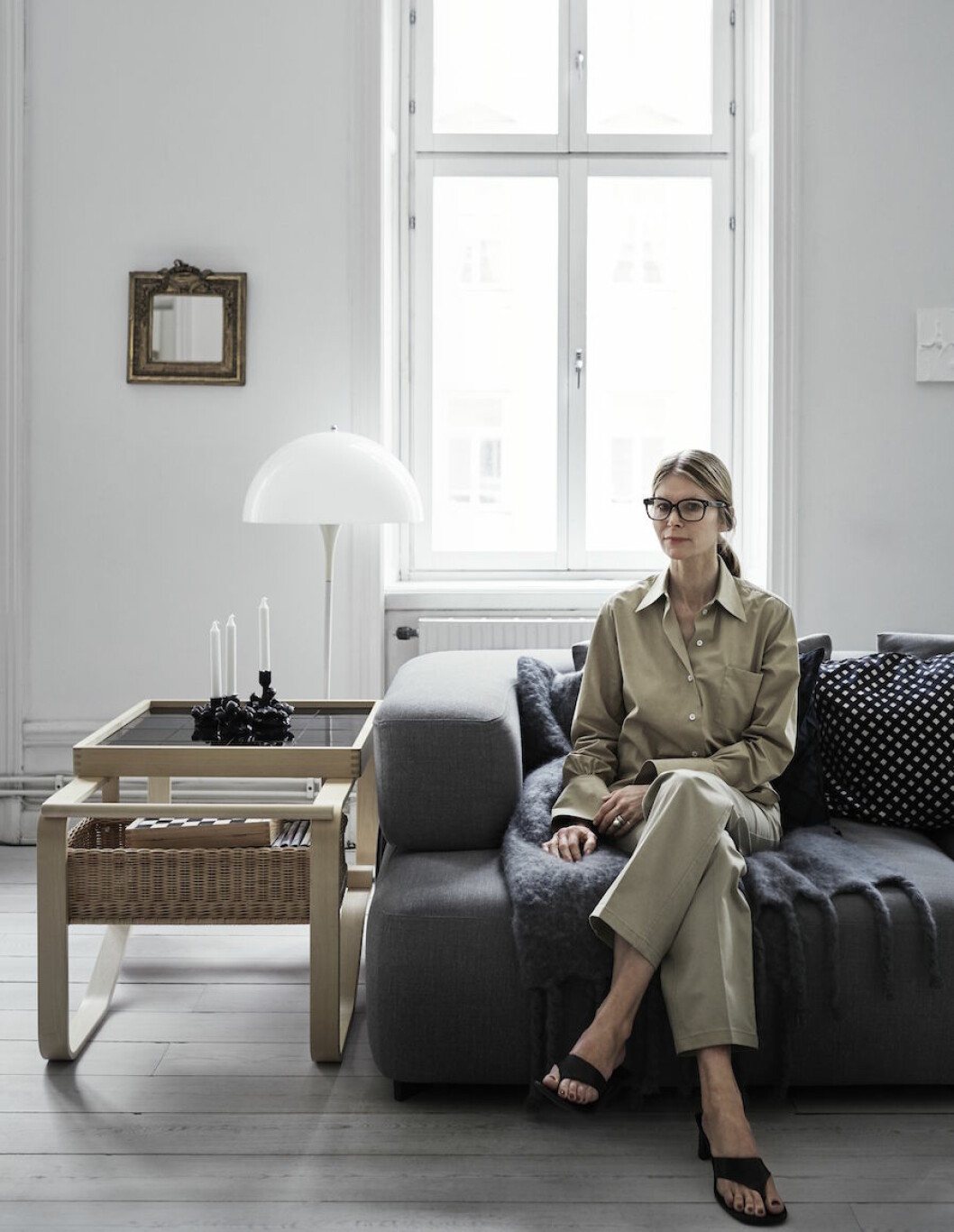 <em>Kläder från Arket. Ramen till den lilla spegeln har hennes morfar gjort, han jobbade som förgyllare. </em> Anna Teurnell sitter i sin soffa i kläder från Arket.
