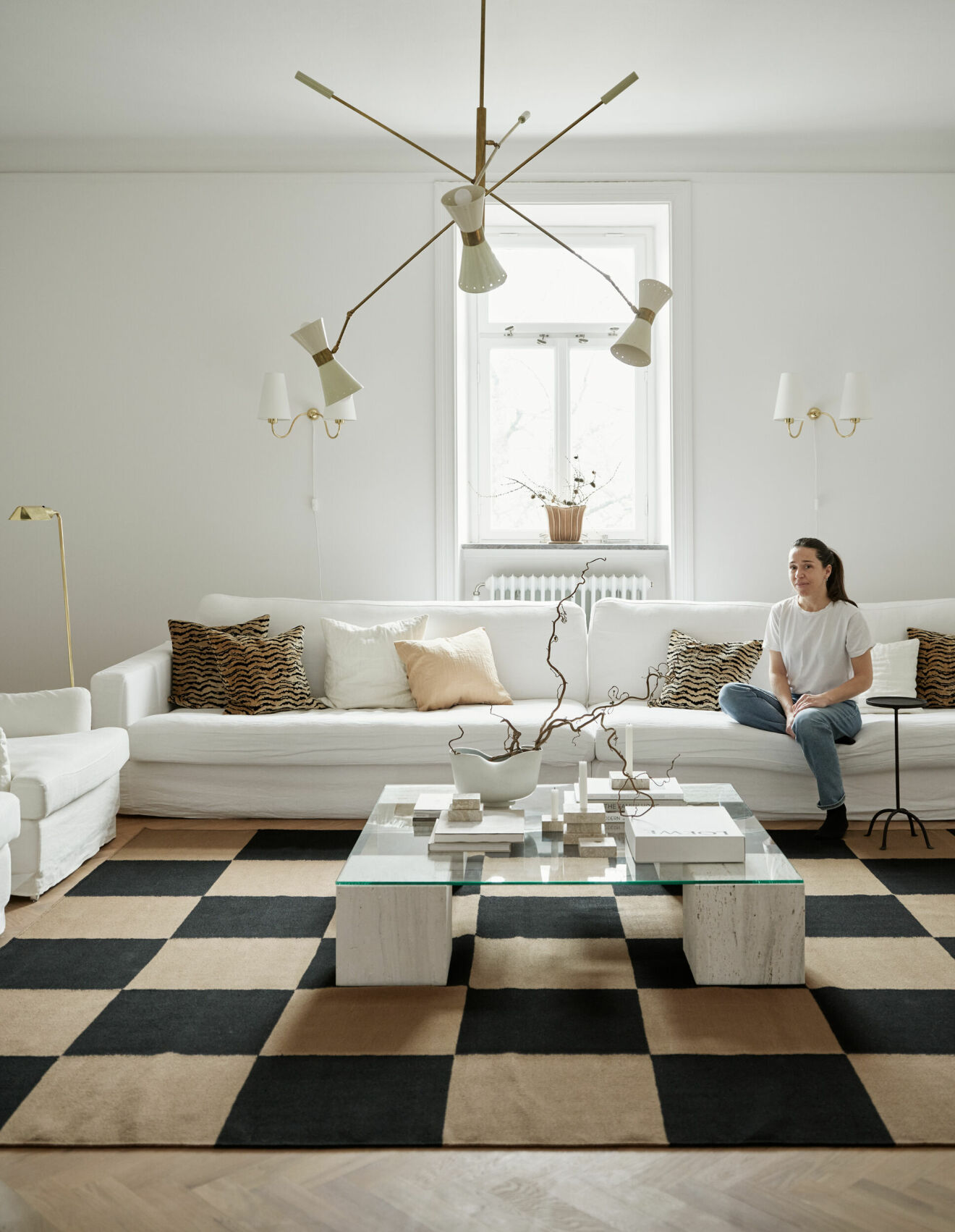 Sofia Ristic i sin soffa från Sweef, vardagsrumsbord designat för Studio Vraco. Mönstrade kuddar, Svenskt tenn.