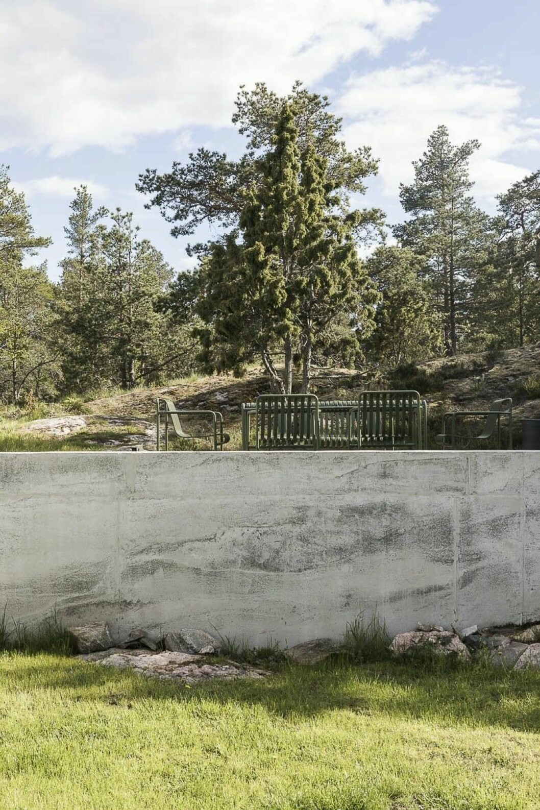 Betongmuren som stagar upp en av uteplatserna jobbar ihop med berget och gör så att uteplatsen kommer lite högre upp och ger en helt ny utsikt mot vattnet. Utemöblerna är från Hay och modellen heter Palissade.