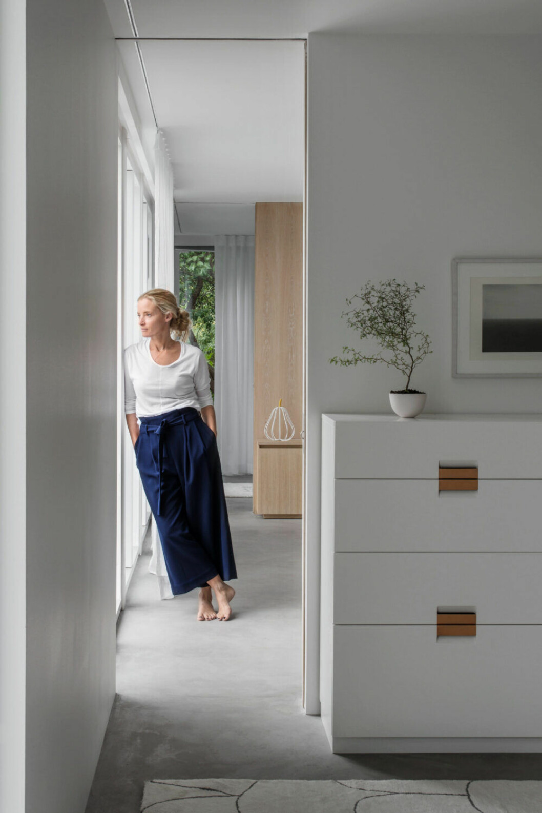 I utbyggnaden på husets trädgårdssida är skjutdörrarna placerade vid fönstret. När de är öppna bildas en korridor mot trädgården där dagsljuset flödar in. I förgrunden byrån Frame, design Anya Sebton och Eva Lilja Löwenhielm för Asplund collection. På sidobordet i tv- rummet står ett päron från Marni. Sandra Asplund