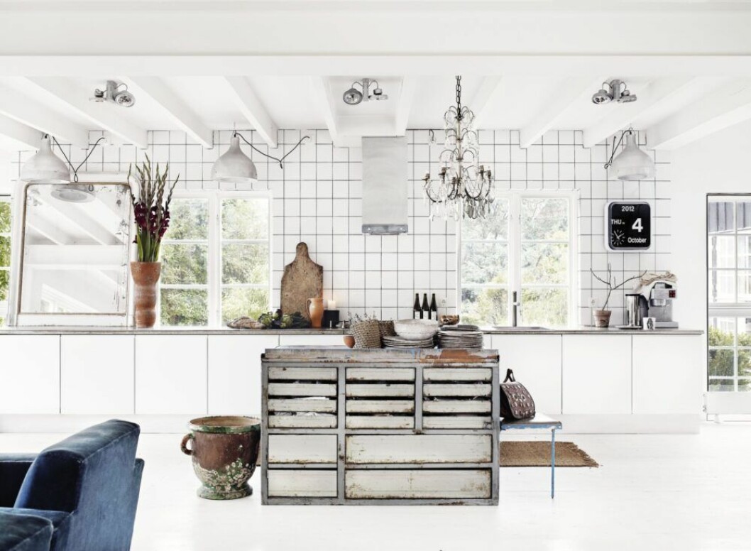 Förvaringen är ett hopplock av Ikea-stommar, luckor från Studio 10 och en hemgjuten bänkskiva i betong. Mitt i köket står köksön från Magasin 36 som är »mer snygg än praktisk – som så mycket annat hemma hos oss«. Kakel i format 15 x 15 centimeter valdes för att ge fransk industrikänsla. 1800-talsurnan på golvet är fransk. Kristallkronan är från 1700-talet. »Den är en av mina käraste ägodelar som jag aldrig säljer.«