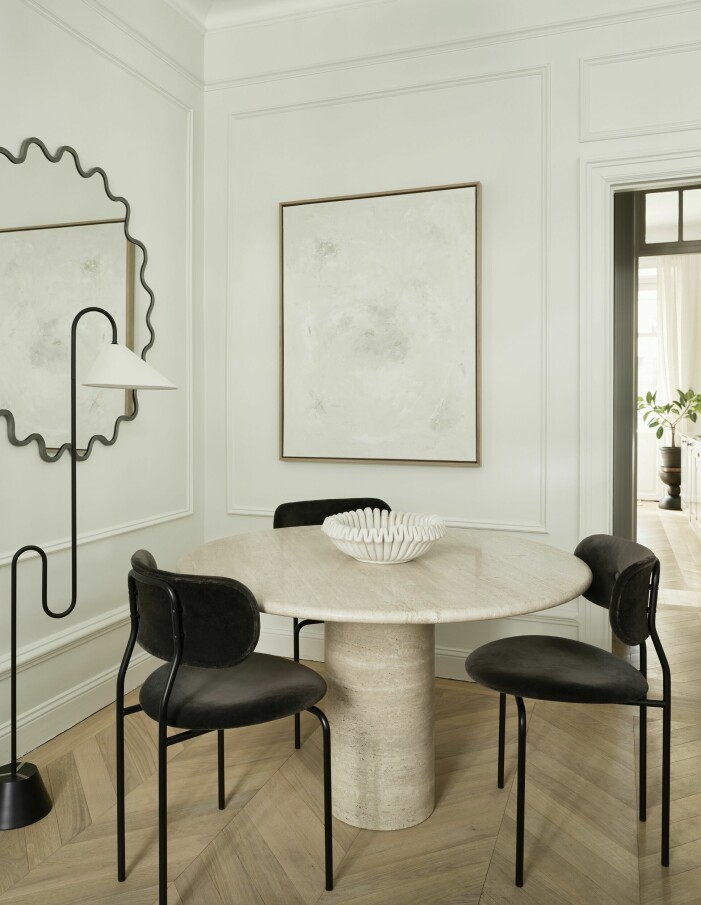 I vardagsrummet finns en liten sittgrupp för middagar med vänner och familj. Travertinbordet är från Galleri Sylvia Enget och stolarna från Gubi. Spegel, Udiso, lampa Roattino av Eileen Gray och konstverk av Mattias. Sittgrupp för middagar.