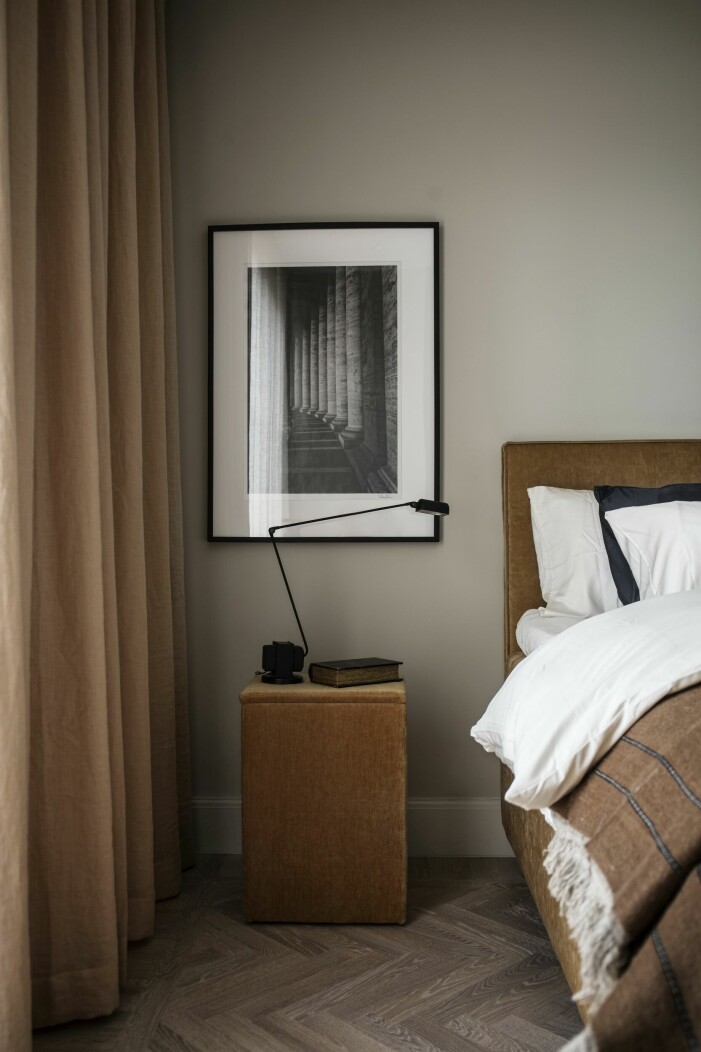 Säng, sängbord och sängkläder från Elgen Studios Hotel collection. Fotokonst av Rickard Eriksson. Murrigt sovrum med mörkbruna detaljer