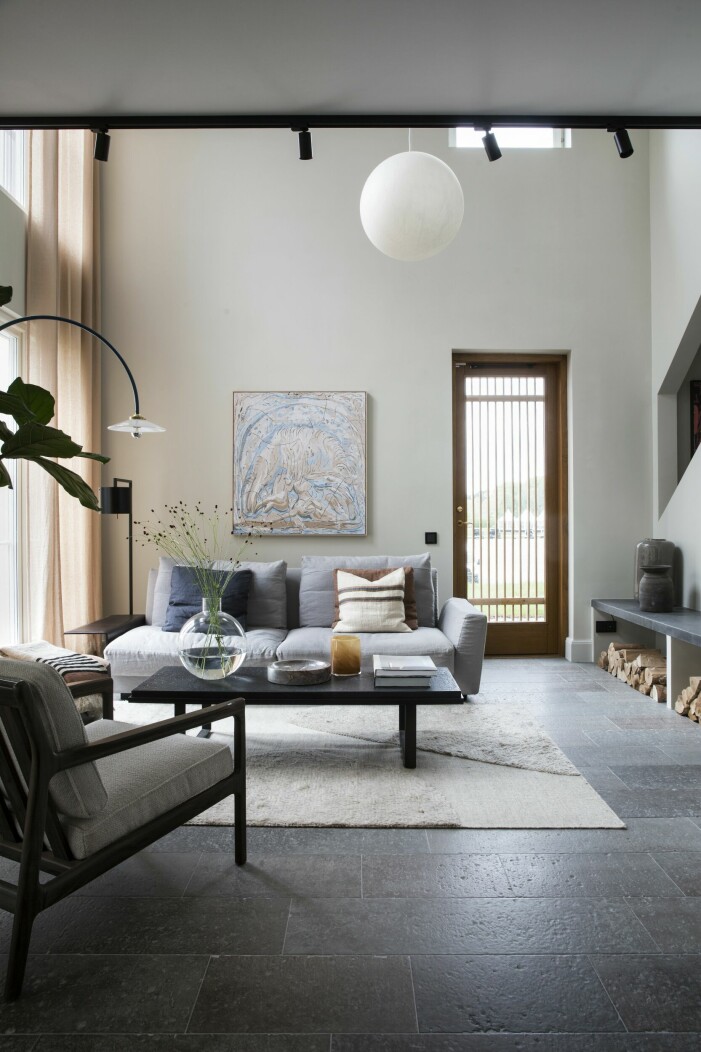 Takhöjden på sex meter gör vardagsrummet luftigt och lockande. På väggen konst av Rebecka Bebben Andersson. Soffa med sittpuff, Knoll. Soffbord och fåtölj, Ethnicraft/Posh living. Glasvas <span class=" italic" data-lab-italic_desktop="italic">Pallo</span>, Carina Seth Anderson för Skruf. Matta, Layered. Golvlampa, Muller van Severen för Valerie objects. Naturnära vardagsrum