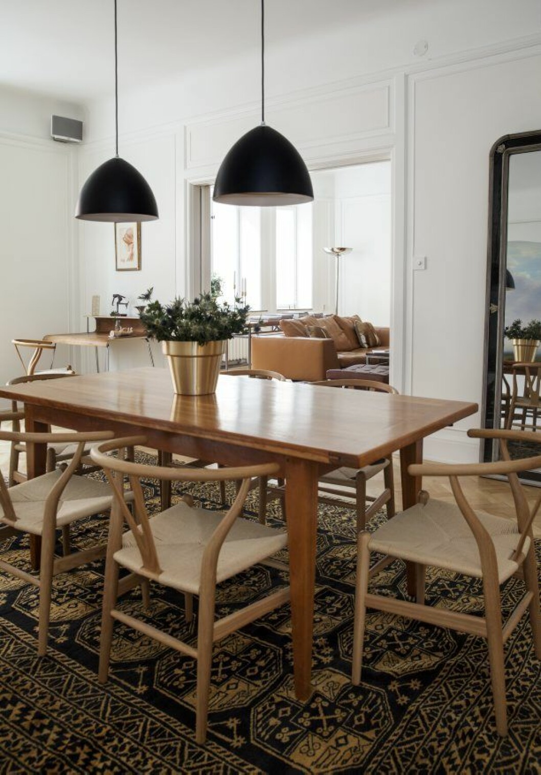 Våningen är sparsamt möblerad med designklassiker och arvegods. Matsalbord köpt i antikaffär. Hans Wegners Y-stolar står placerade runt om. På bordet tronar Monica Försters blomkruka för Skultuna. Skultuna