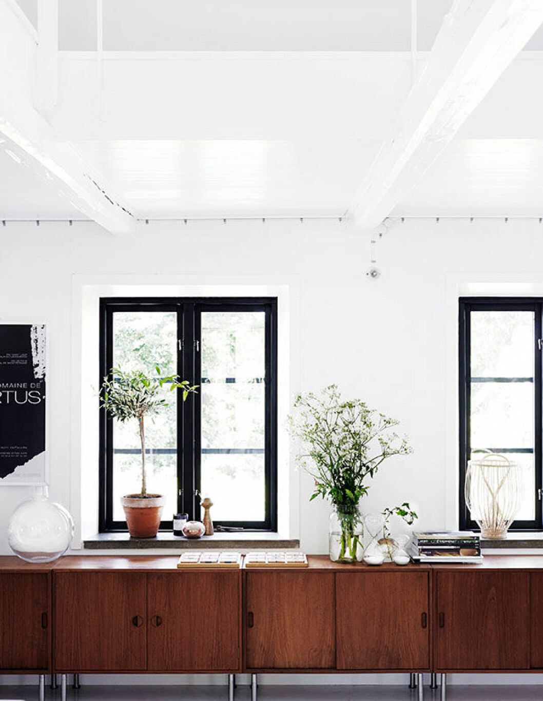 <em>Köket är delvis inrett som vardagsrum. Teakskåpen är inropade på auktion. Timglasen är köpta i New York, den runda glasvasen, Carina Seth Andersson. Fruktkorgen i fönstret, Urban Living. Den svartvita planschen är köpt på favoritvingården i distriktet Pic Saint Loup i Frankrike. </em> sofia odier monokromt skane 11