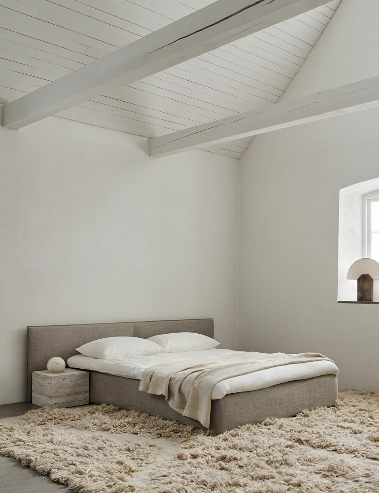Sovrum med högt i tak och minimalistisk ombonad inredning