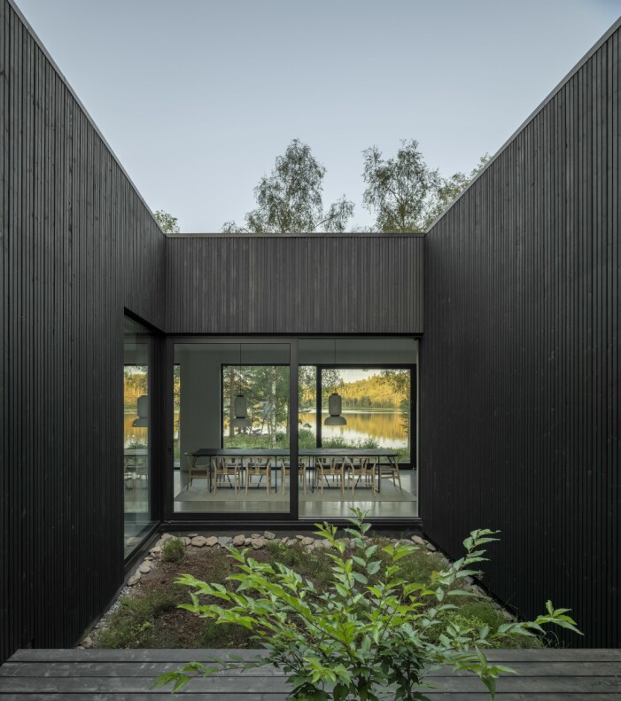 Från atriumgårdens lilla terrass kan man se rakt genom huset, förbi matplatsen och vidare ner mot sjön. Stort öppet atrium mitt i huset.