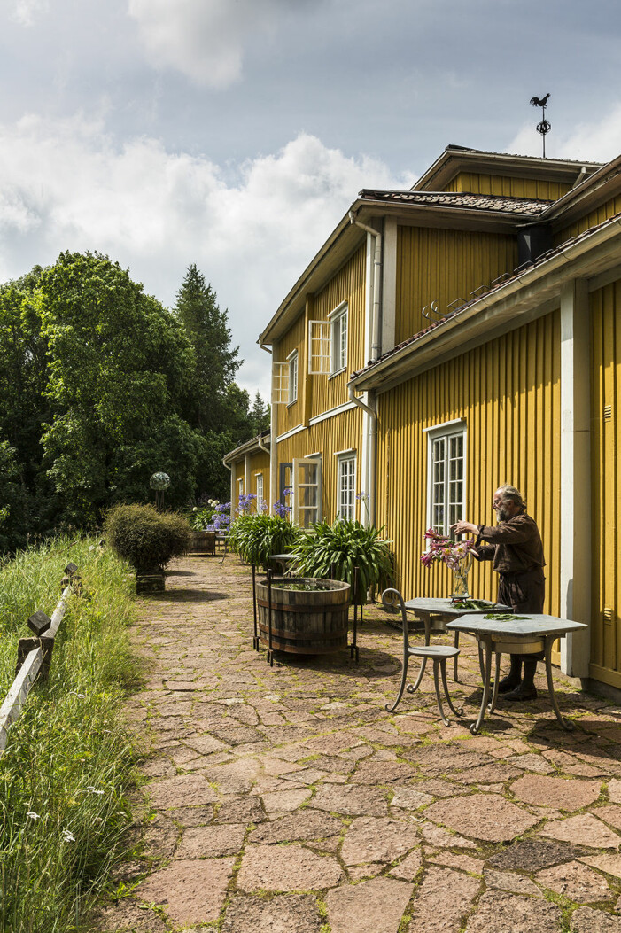 Tage Andersen i sitt rätta element med bukett. Vacker ölandssten täcker uteplatsen på baksidan. Tage Andersens Gunillaberg är till salu. Trädgården bjuder på buxbom och grusade gångar. Och mängder med liljor.